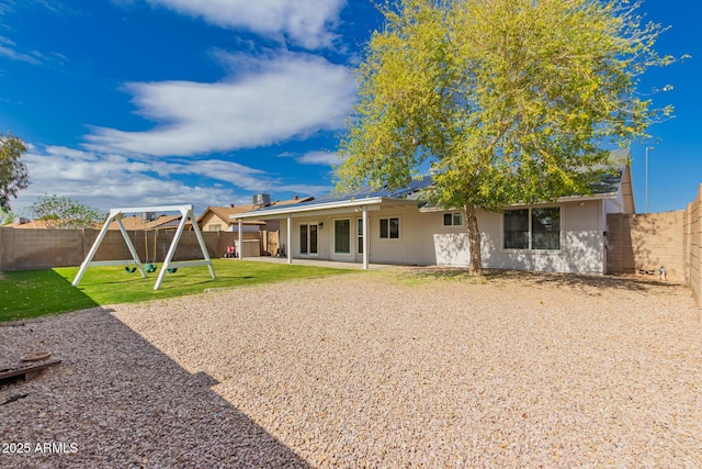 rear view of house with a fenced backyard, a patio, a playground, and a yard