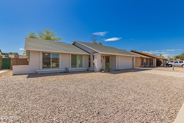 view of front of home featuring concrete driveway, fence, a garage, and stucco siding