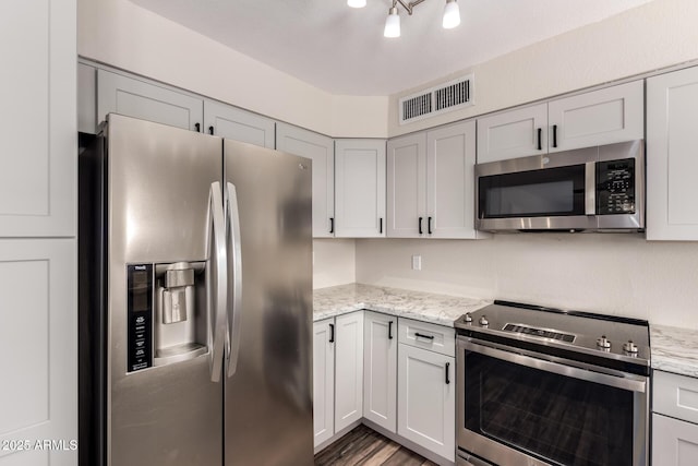 kitchen featuring light stone counters, visible vents, light wood-style floors, and appliances with stainless steel finishes