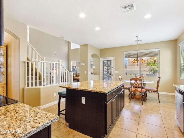 kitchen with light stone counters, decorative light fixtures, light tile patterned floors, and a kitchen island