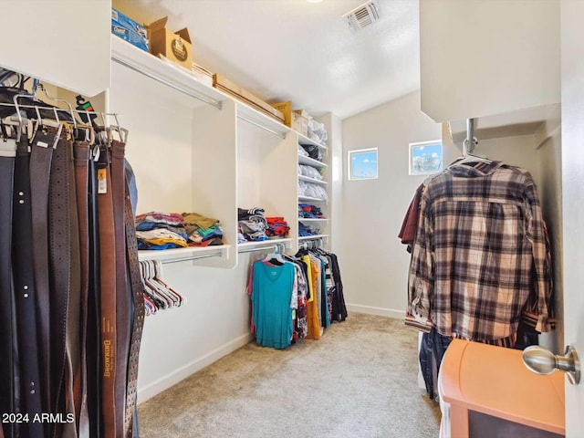 spacious closet with vaulted ceiling and light colored carpet