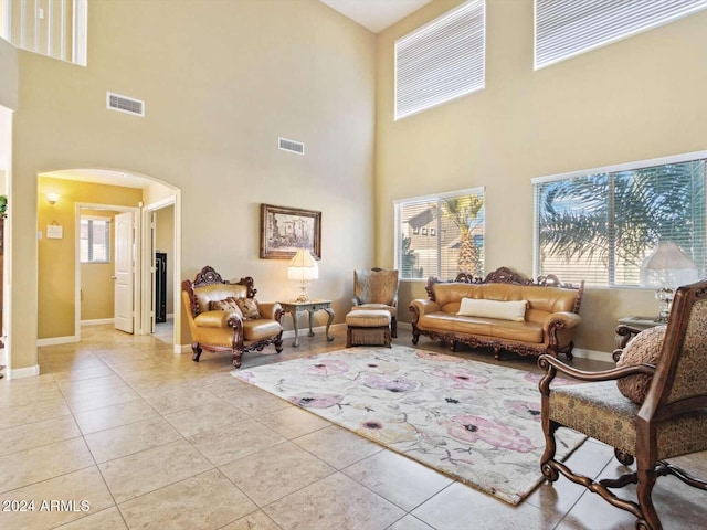 living room featuring a towering ceiling, plenty of natural light, and light tile patterned floors