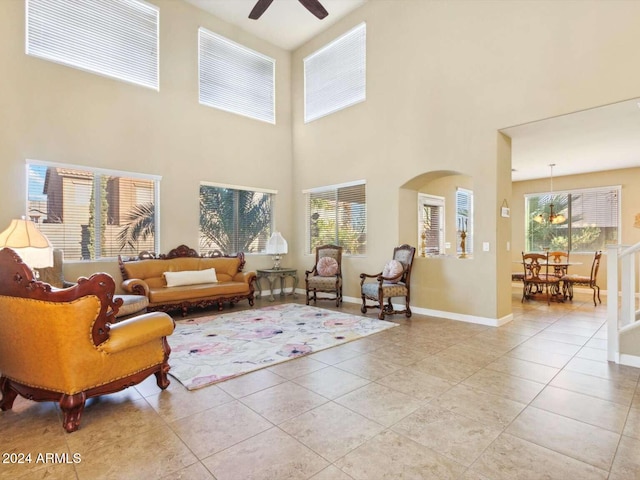 living room featuring a towering ceiling, ceiling fan, and light tile patterned floors