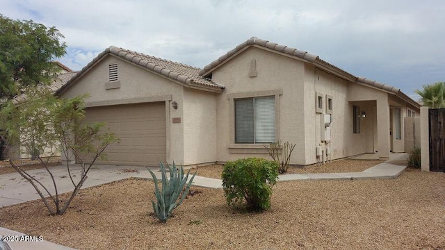 view of front facade featuring a tiled roof, driveway, stucco siding, and an attached garage