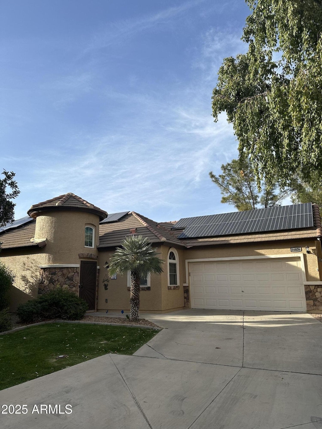 view of front facade with driveway, a garage, solar panels, and stucco siding