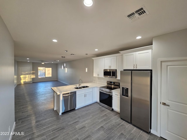 kitchen with sink, stainless steel appliances, kitchen peninsula, and white cabinets