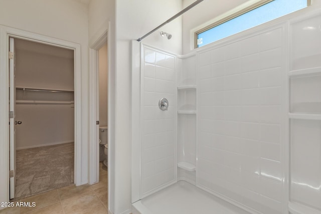 bathroom featuring tile patterned flooring, toilet, and walk in shower