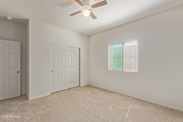 unfurnished bedroom with ceiling fan, light carpet, and a closet