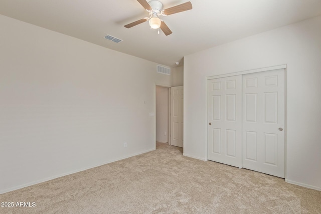 unfurnished bedroom with a closet, light colored carpet, and ceiling fan