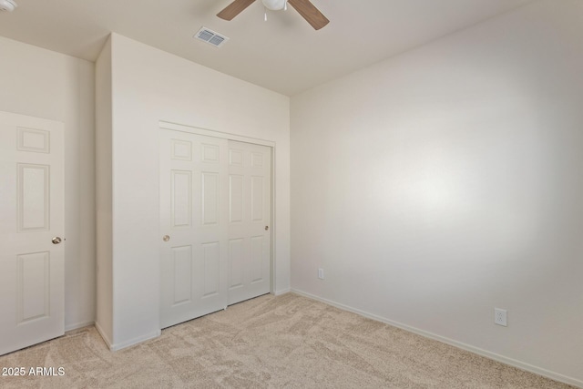 unfurnished bedroom with light colored carpet, a closet, and ceiling fan