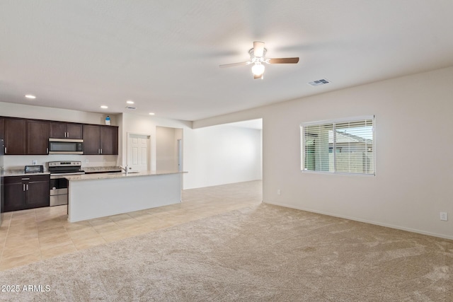 kitchen with a kitchen island with sink, light carpet, sink, ceiling fan, and stainless steel appliances