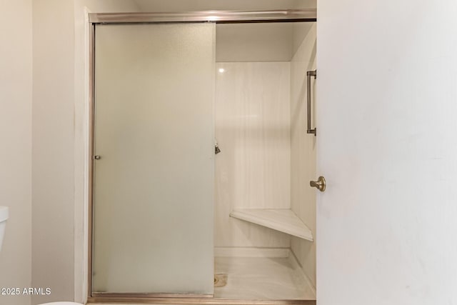 bathroom with a shower with door and toilet