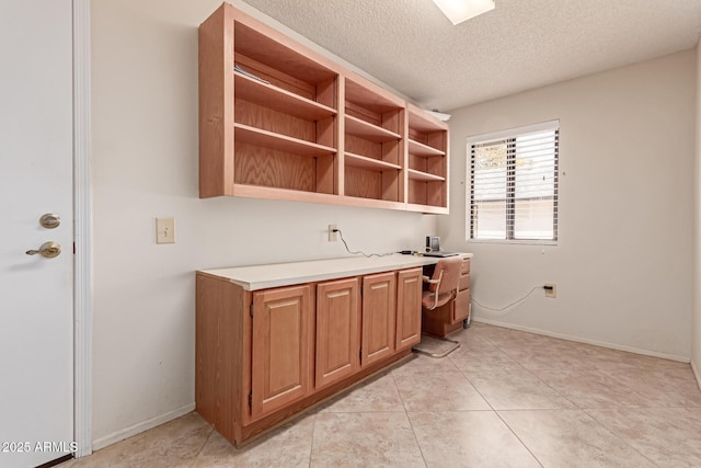 kitchen featuring light tile patterned flooring, built in desk, and a textured ceiling