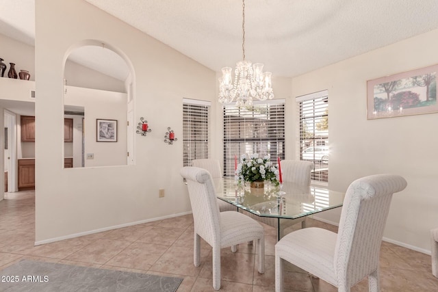 tiled dining space with a chandelier, vaulted ceiling, and a textured ceiling