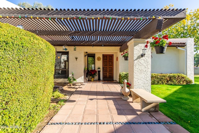 property entrance with a yard, a pergola, and a patio area