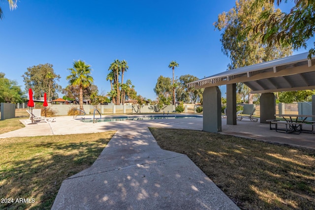 surrounding community with a pool, a lawn, and a patio area