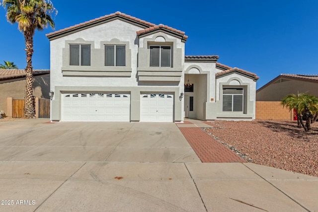 mediterranean / spanish-style home featuring stucco siding, concrete driveway, an attached garage, fence, and a tiled roof