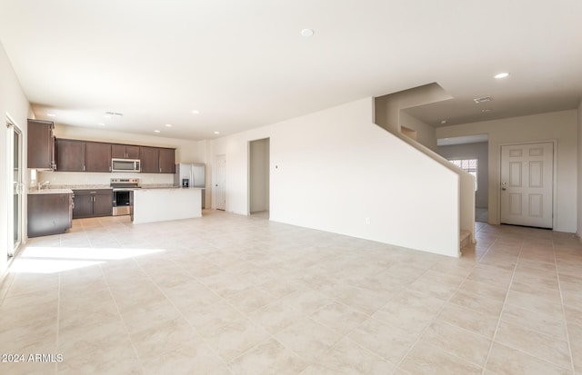 unfurnished living room featuring light tile patterned floors and sink