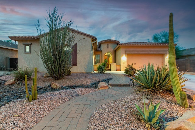 mediterranean / spanish home with a tiled roof, an attached garage, and stucco siding