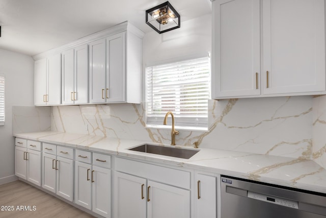 kitchen featuring light wood finished floors, white cabinetry, a sink, stainless steel dishwasher, and backsplash