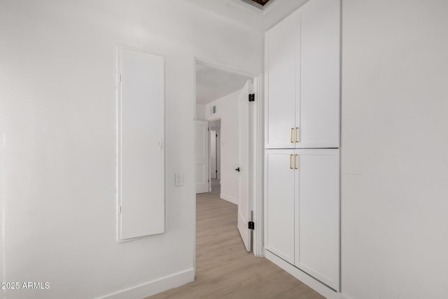 corridor with light wood-type flooring and baseboards