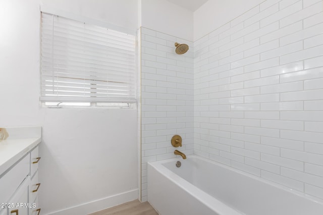 full bath featuring vanity, bathing tub / shower combination, baseboards, and wood finished floors