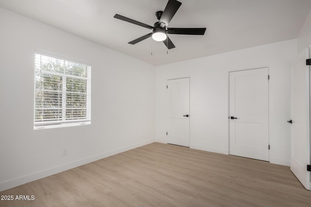 unfurnished bedroom with wood finished floors, baseboards, and two closets