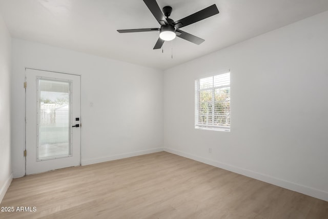 empty room featuring a ceiling fan, light wood-type flooring, and baseboards