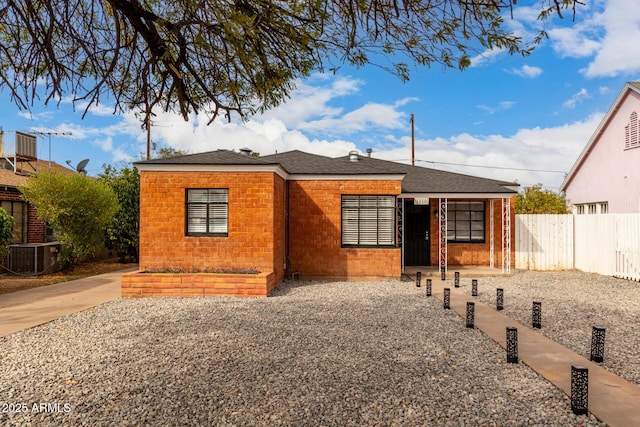 view of front of property featuring brick siding, cooling unit, a shingled roof, and fence