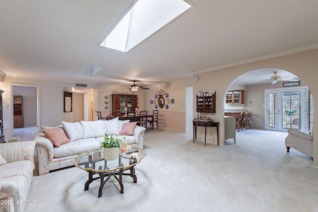 carpeted living room featuring ceiling fan, crown molding, and a skylight