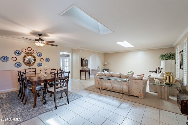 dining room with a skylight, ceiling fan, crown molding, and light tile patterned flooring