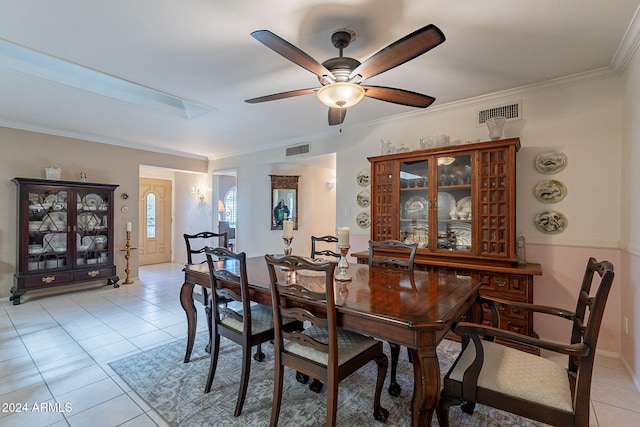 dining room featuring light tile patterned floors, a skylight, ceiling fan, and ornamental molding