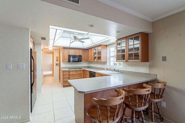 kitchen with black appliances, sink, ceiling fan, a kitchen bar, and kitchen peninsula