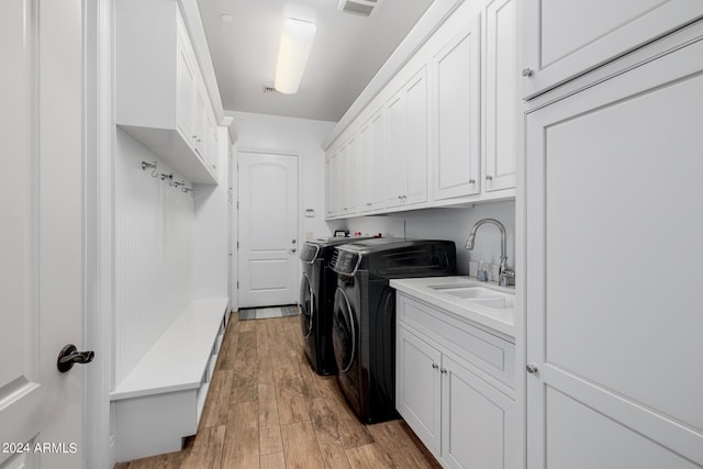 washroom with visible vents, cabinet space, light wood-style flooring, a sink, and independent washer and dryer