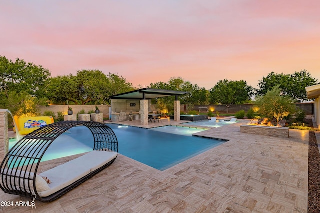 view of swimming pool featuring a patio, an outdoor kitchen, a fenced backyard, a fire pit, and a fenced in pool