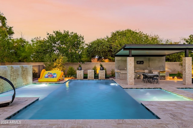 view of swimming pool featuring a fenced backyard, an outdoor kitchen, a fenced in pool, and a patio