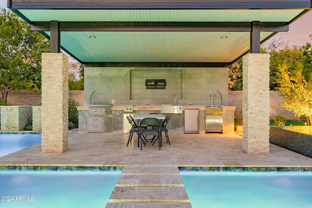 view of pool with a patio, an outdoor kitchen, a sink, a grill, and fence