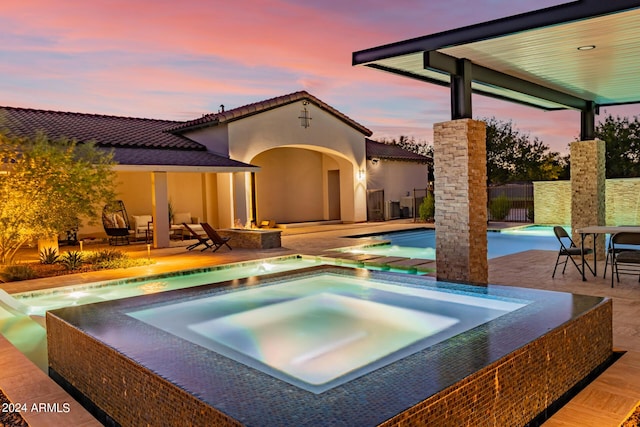 pool with fence, a fire pit, a patio, and an in ground hot tub