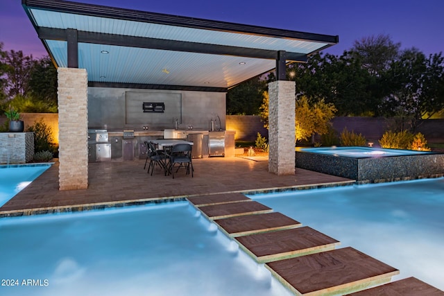 view of pool with a pool with connected hot tub, an outdoor kitchen, a patio area, a grill, and fence