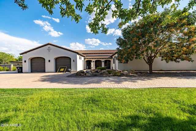 mediterranean / spanish-style home featuring a garage, a tiled roof, decorative driveway, and a front yard