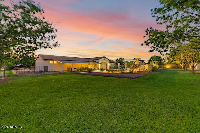 rear view of house featuring fence and a lawn