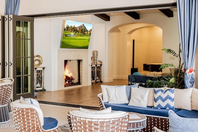 living room featuring tile patterned flooring, a fireplace, arched walkways, and beam ceiling