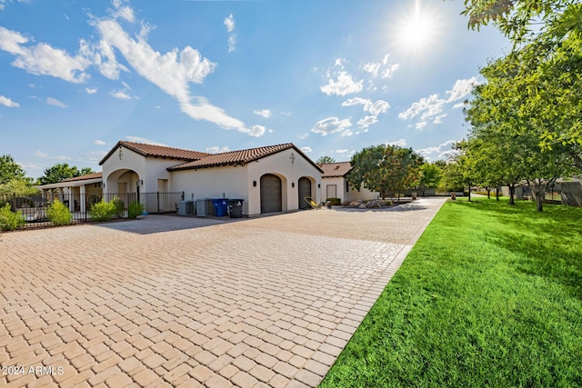 mediterranean / spanish-style home with fence, a tiled roof, decorative driveway, stucco siding, and a front lawn