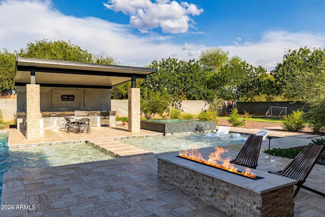 view of patio with exterior kitchen, a fenced backyard, and a fire pit