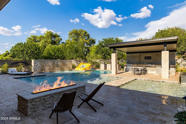 view of swimming pool with an outdoor fire pit, an outdoor kitchen, a fenced in pool, fence private yard, and a patio area