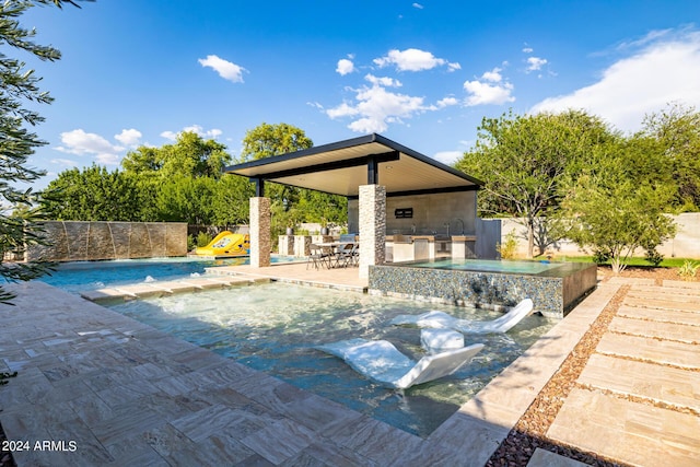 pool with an in ground hot tub, a patio area, and fence