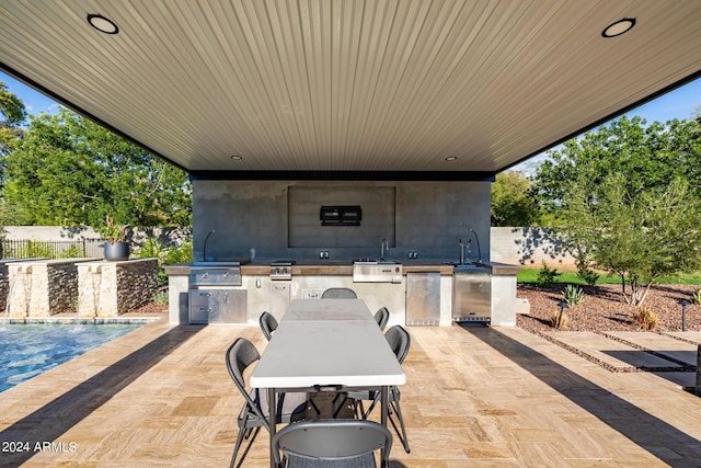 view of patio / terrace with exterior kitchen, fence, grilling area, and a sink