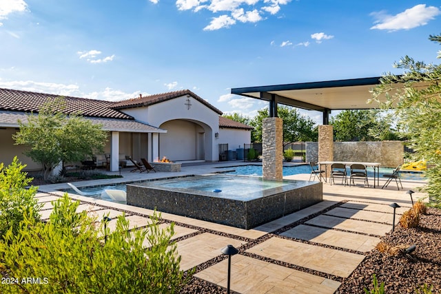 view of patio with an in ground hot tub, fence, and an outdoor pool