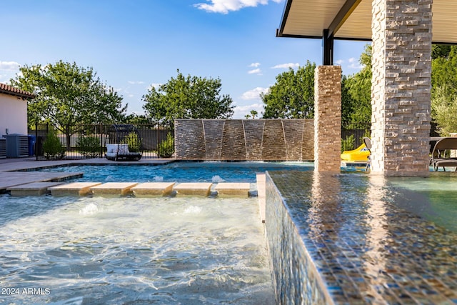 view of swimming pool featuring cooling unit, fence, and a pool with connected hot tub