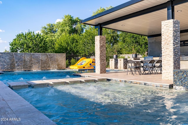 view of swimming pool with a pool with connected hot tub, fence, outdoor wet bar, and area for grilling